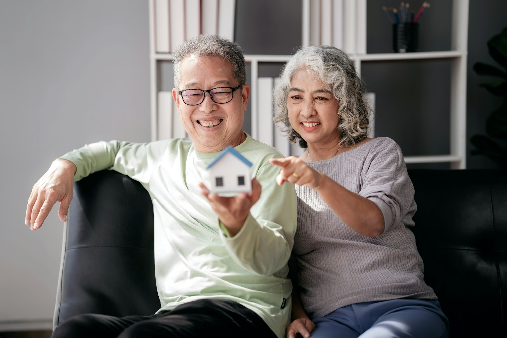 senior-couple-holding-house-model-for-buying-in-life-retirement.jpg